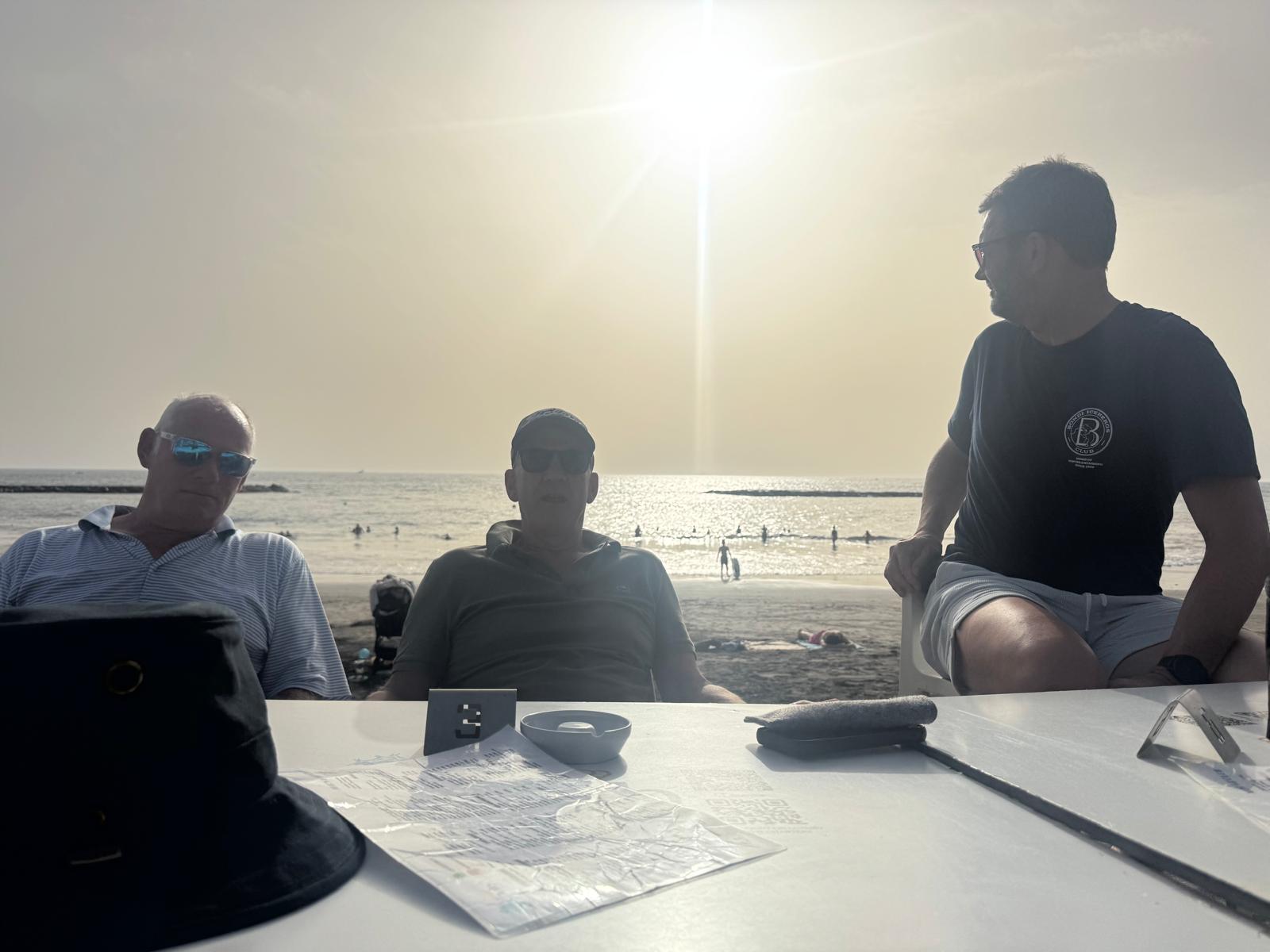 Three players at a beachside table in the morning sun